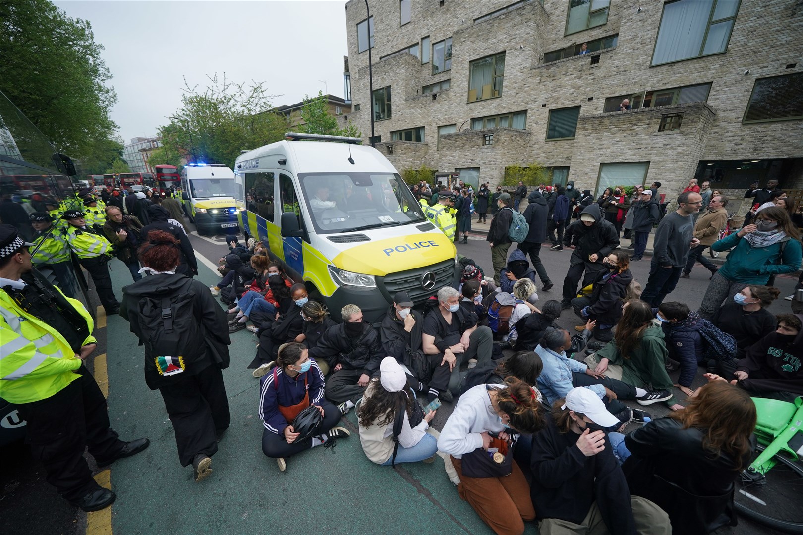 Protesters sat in front of a police van after forming a blockade around the coach (Yui Mok/PA)